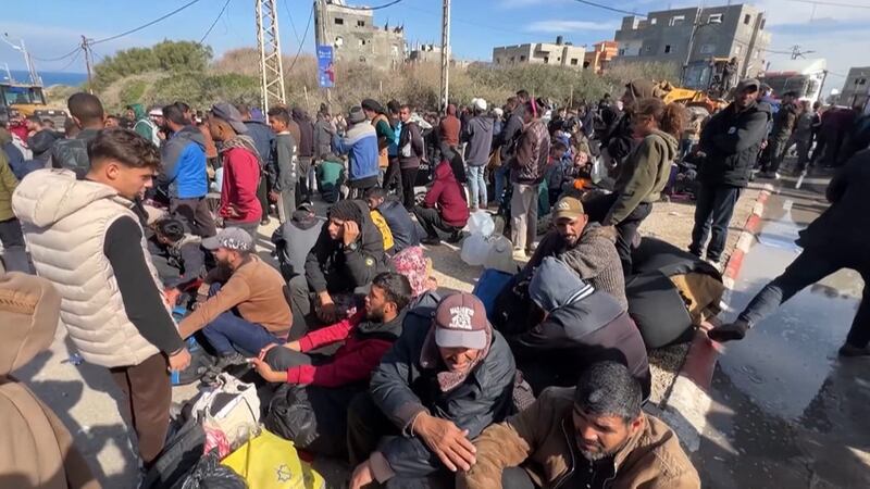 Carrying their belongings, Palestinians gather along the street sides Saturday, January 25,...