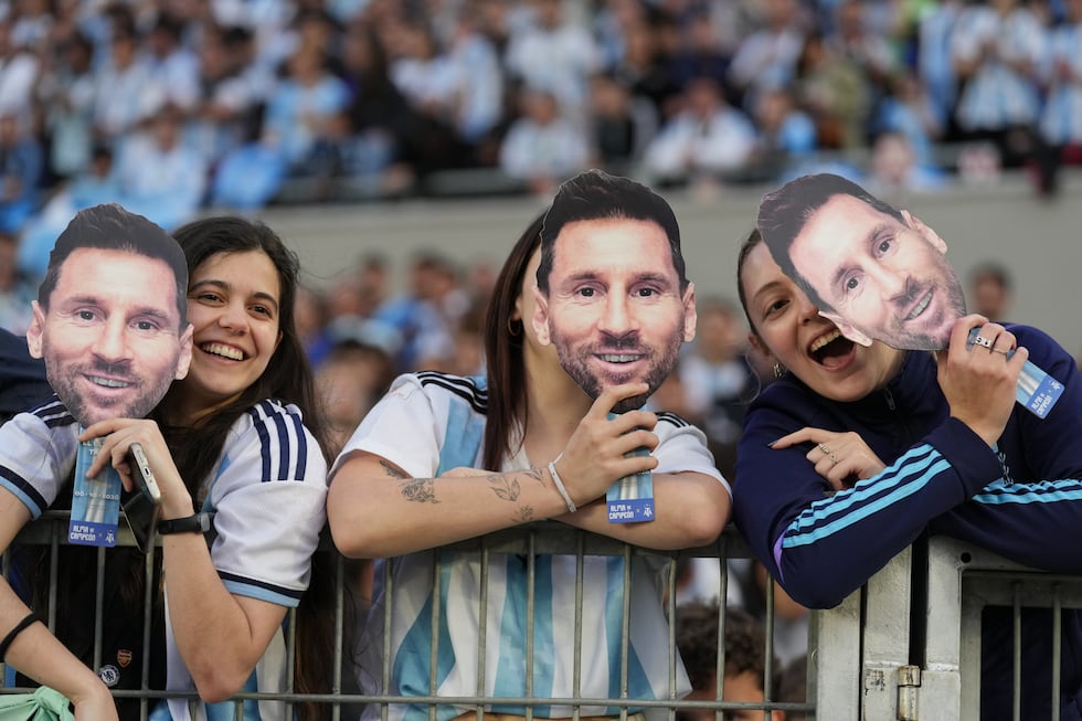 Fans hold masks depicting Lionel Messi before his final match for Argentina, a soccer friendly...
